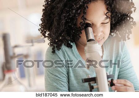 Stock Photography - African American girl using microscope in science classroom. Fotosearch