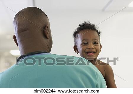 Picture - African American male medical professional holding baby. Fotosearch