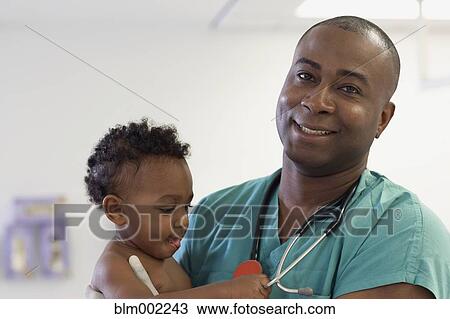 Stock Image - African American male medical professional holding baby. Fotosearch