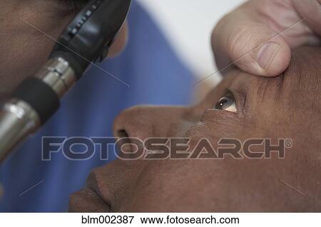 Stock Photo - African American man having eye examined. Fotosearch
