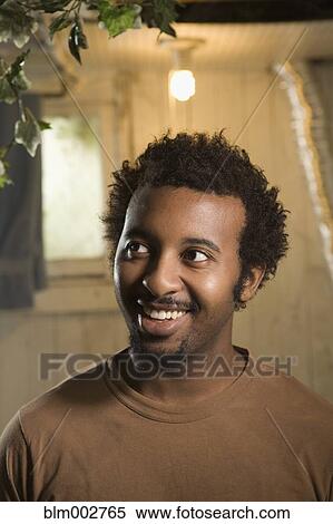 Stock Photography - African American man smiling with light bulb overhead. Fotosearch