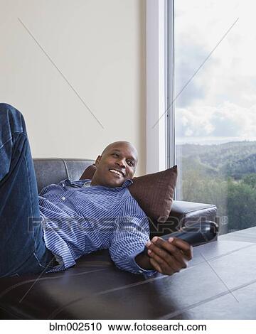 Stock Image - African American man watching television. Fotosearch