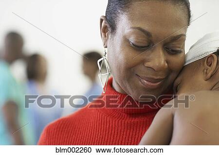 Stock Image - African American mother hugging bandaged baby. Fotosearch