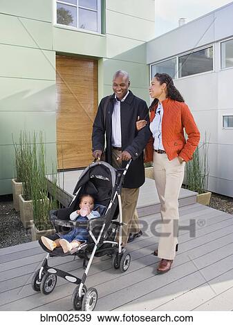 Stock Photo - African American parents pushing baby in stroller. Fotosearch