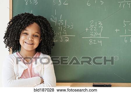 Stock Photo - African American student smiling near chalkboard in classroom. Fotosearch