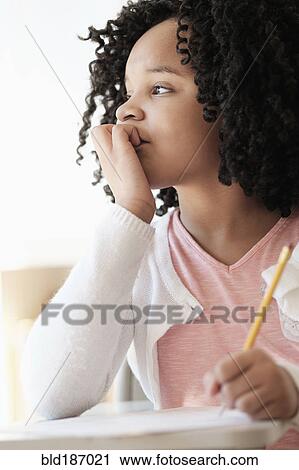 Stock Image - African American student writing in classroom. Fotosearch