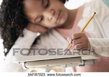 Stock Image - African American student writing in classroom. Fotosearch