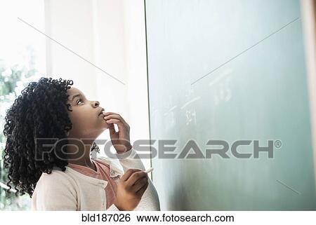 Stock Photograph - African American student writing on chalkboard in classroom. Fotosearch