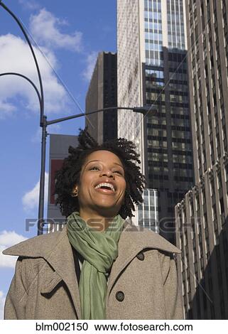 Stock Image - African American woman laughing in urban scene. Fotosearch
