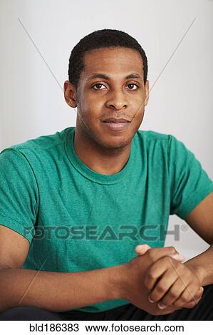 Stock Image - African American woman smiling with hands clasped. Fotosearch