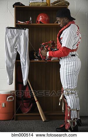 Picture - African baseball catcher in locker room. Fotosearch