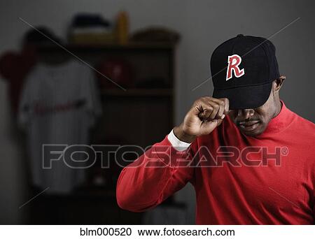 African baseball player adjusting cap in locker room View Large Photo Image Stock Image - African baseball player adjusting cap in locker room. Fotosearch