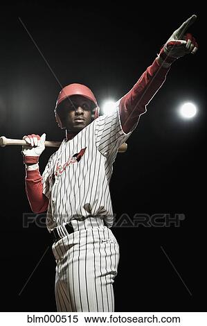 Stock Photography - African baseball player holding bat and pointing. Fotosearch
