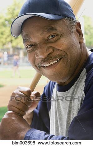 Stock Photo - African baseball player holding bat. Fotosearch