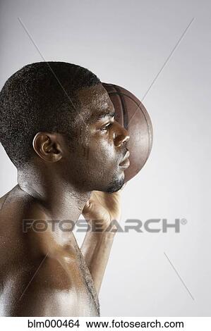 Picture - African basketball player holding basketball. Fotosearch