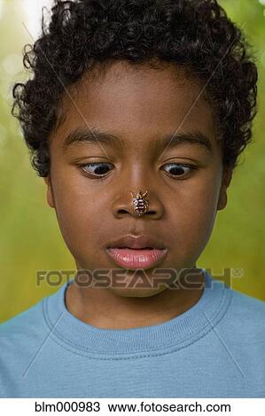 Stock Image - African boy with insect on his nose. Fotosearch