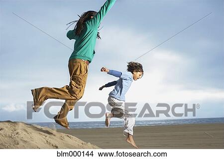 Picture - African brothers jumping on sand dune. Fotosearch