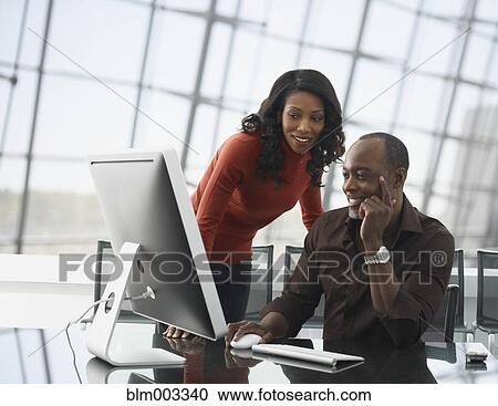 Stock Image - African business people looking at computer in office. Fotosearch