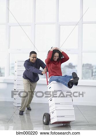 Stock Image - African business people moving boxes in new office. Fotosearch