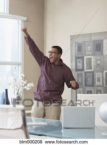 Stock Photo - African businessman cheering in office. Fotosearch