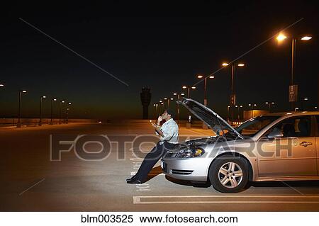 Stock Photography - African businessman having car trouble in parking lot. Fotosearch