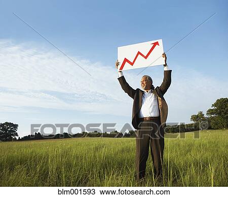 African businessman holding up arrow graph in field View Large Photo Image Stock Image - African businessman holding up arrow graph in field. Fotosearch