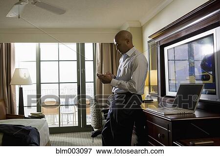 Stock Photo - African businessman in hotel using cell phone. Fotosearch
