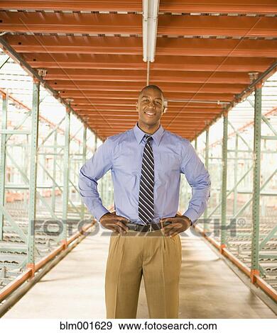 Stock Photo - African businessman in warehouse hallway. Fotosearch