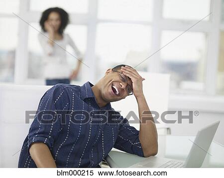 Stock Photography - African businessman laughing in office. Fotosearch
