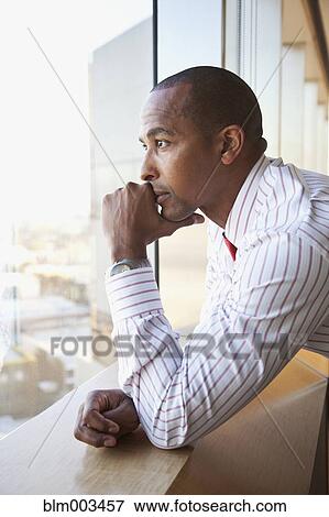 Stock Photo - African businessman leaning on windowsill. Fotosearch