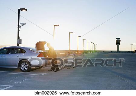 African businessman loading luggage into car View Large Photo Image Stock Photograph - African businessman loading luggage into car. Fotosearch