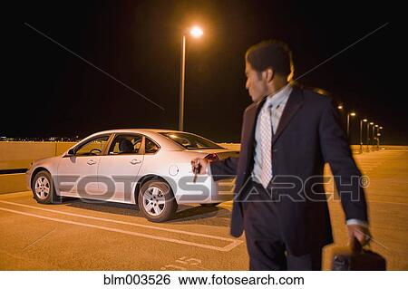 Stock Photograph - African businessman locking car in parking lot. Fotosearch