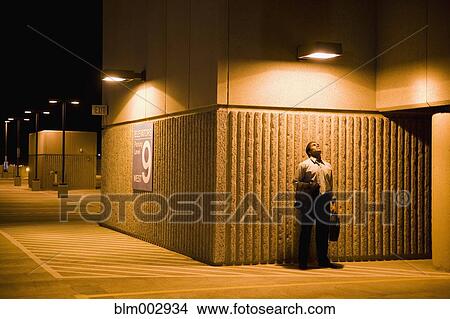 Picture - African businessman looking at light in parking lot. Fotosearch