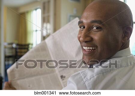 Stock Image - African businessman reading newspaper. Fotosearch