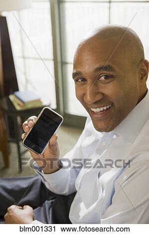 Stock Image - African businessman showing cell phone. Fotosearch