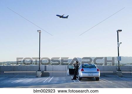 Stock Image - African businessman standing by car at airport. Fotosearch