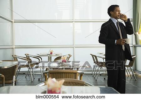 Picture - African businessman talking on cell phone in cafe. Fotosearch