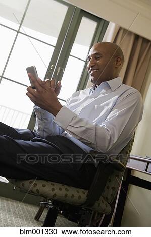 Stock Image - African businessman using cell phone. Fotosearch