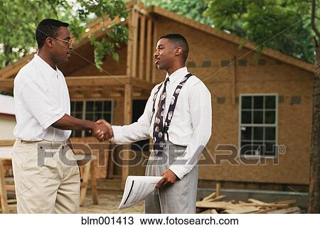 Stock Image - African businessmen shaking hands outside new home. Fotosearch