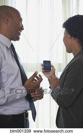 Stock Photo - African businesspeople looking at cell phone. Fotosearch