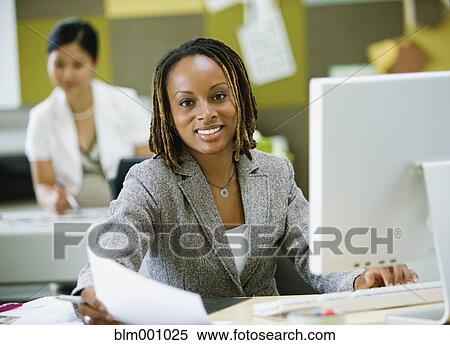 Stock Photography - African businesswoman working at desk. Fotosearch