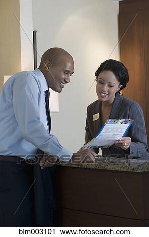 Stock Image - African concierge helping businessman. Fotosearch