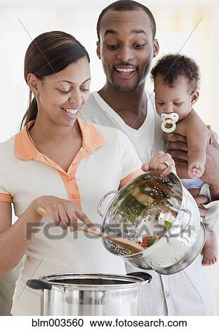 Stock Image - African couple and baby cooking. Fotosearch