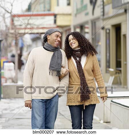 Stock Photo - African couple arm in arm walking on sidewalk. Fotosearch