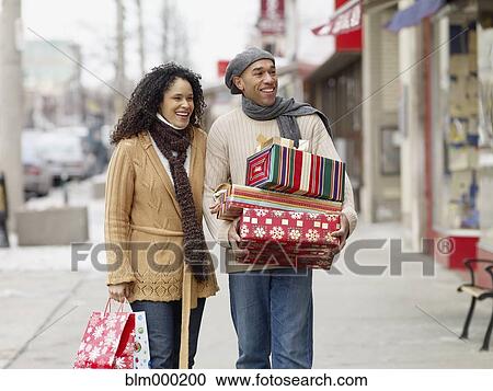 Stock Image - African couple carrying Christmas presents. Fotosearch