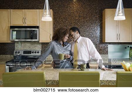 Stock Photography - African couple drinking coffee in modern kitchen. Fotosearch