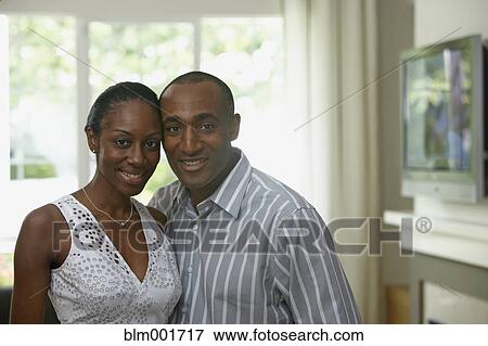 Stock Photo - African couple hugging in livingroom. Fotosearch