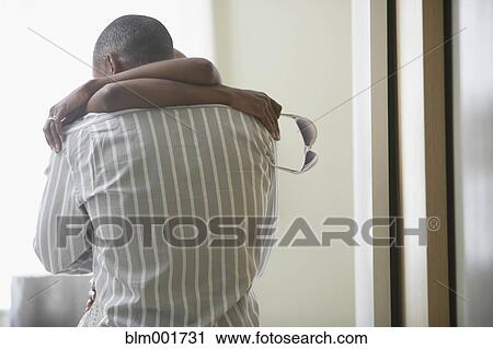 Stock Image - African couple hugging indoors. Fotosearch