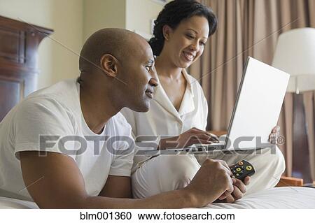 Stock Image - African couple in bed using laptop. Fotosearch