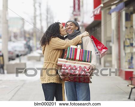 Stock Image - African couple kissing and carrying Christmas presents. Fotosearch